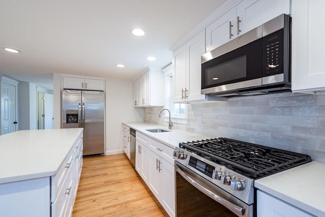 kitchen featuring light wood-style floors, white cabinetry, appliances with stainless steel finishes, and a sink