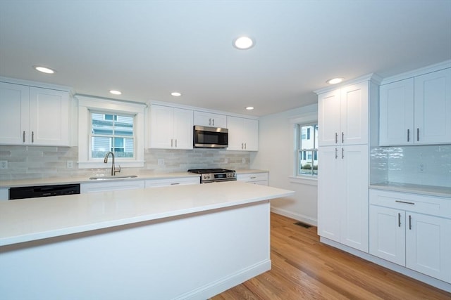 kitchen featuring light wood-style flooring, stainless steel appliances, a sink, visible vents, and white cabinetry