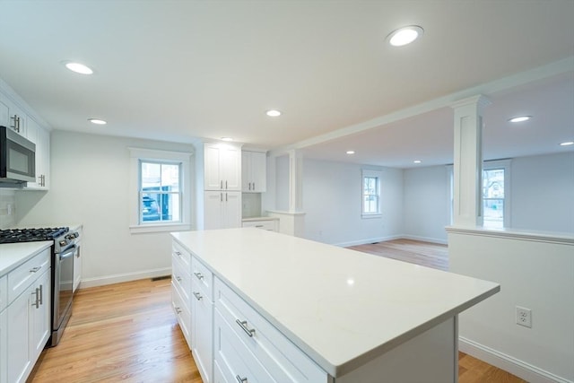 kitchen featuring a kitchen island, appliances with stainless steel finishes, light wood-type flooring, white cabinetry, and recessed lighting