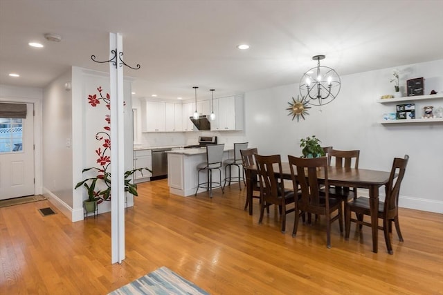 dining space with light wood-type flooring and a notable chandelier