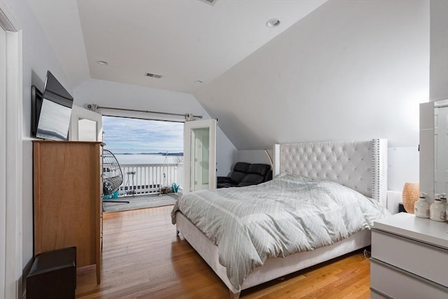 bedroom with access to exterior, hardwood / wood-style floors, and lofted ceiling