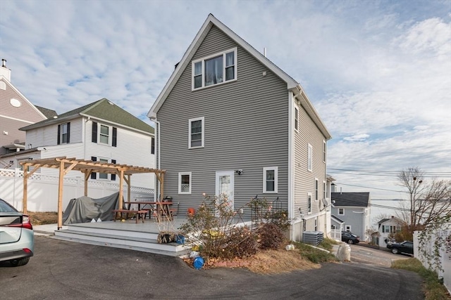 back of property with a pergola, a wooden deck, and central AC unit