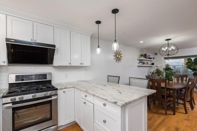 kitchen with kitchen peninsula, gas stove, and white cabinetry