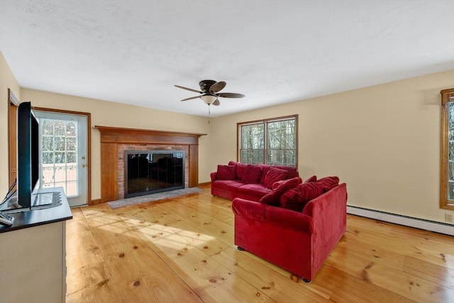 living room featuring ceiling fan, light wood-type flooring, and a baseboard heating unit