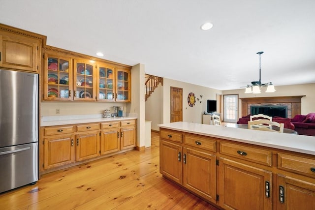 kitchen featuring a chandelier, light hardwood / wood-style flooring, pendant lighting, and stainless steel fridge