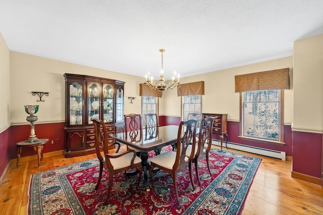 dining room featuring baseboard heating, an inviting chandelier, and light hardwood / wood-style floors