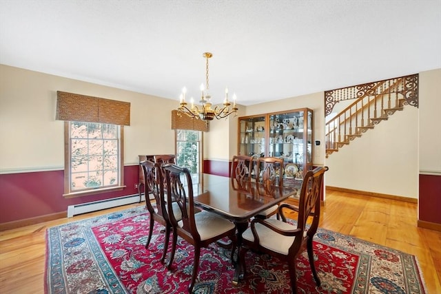 dining area featuring a baseboard heating unit, an inviting chandelier, and wood-type flooring