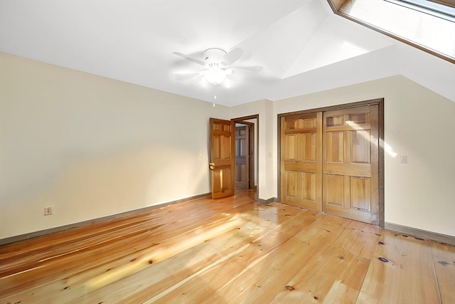 unfurnished bedroom featuring hardwood / wood-style floors, a closet, vaulted ceiling, and ceiling fan