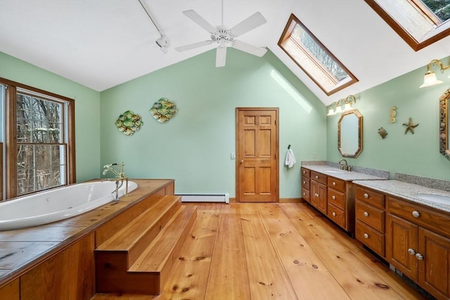 bathroom with wood-type flooring, baseboard heating, lofted ceiling with skylight, track lighting, and vanity