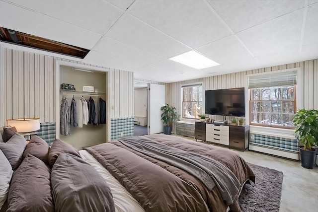 bedroom with a paneled ceiling, a closet, and a baseboard heating unit