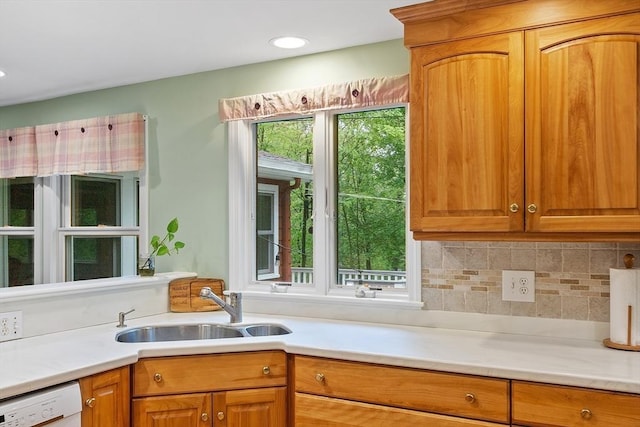 kitchen with white dishwasher, a sink, light countertops, and recessed lighting