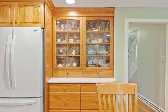 detailed view of freestanding refrigerator, baseboards, and a baseboard radiator