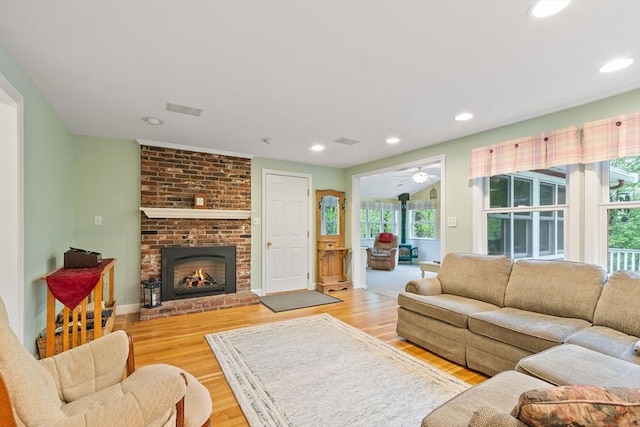 living room with wood finished floors, a brick fireplace, recessed lighting, a ceiling fan, and baseboards
