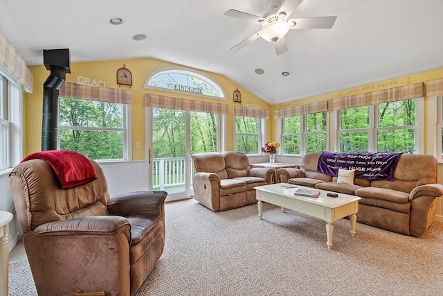 carpeted living area featuring vaulted ceiling, ceiling fan, and a wood stove