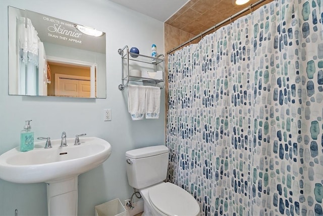bathroom with toilet, a shower with shower curtain, and a sink