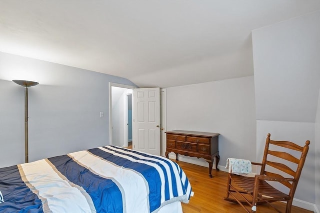 bedroom featuring vaulted ceiling, light wood finished floors, and baseboards
