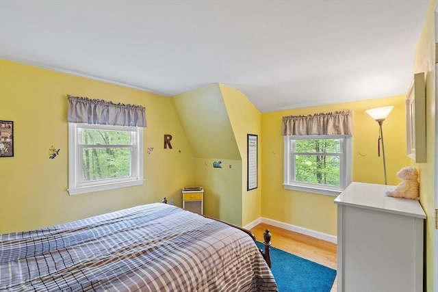 bedroom with wood finished floors, vaulted ceiling, and baseboards