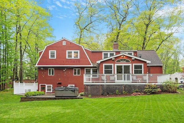 rear view of house featuring a hot tub, a deck, a chimney, and a gambrel roof