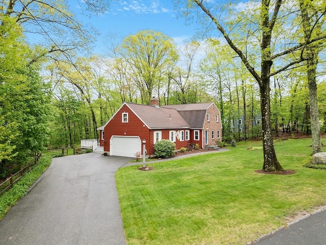 view of front of property with a garage, a front lawn, a chimney, and driveway