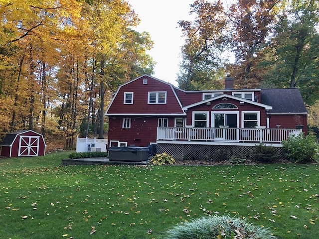 back of house featuring a hot tub, a deck, a chimney, and a yard