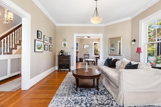 living area with crown molding, baseboards, wood finished floors, and radiator
