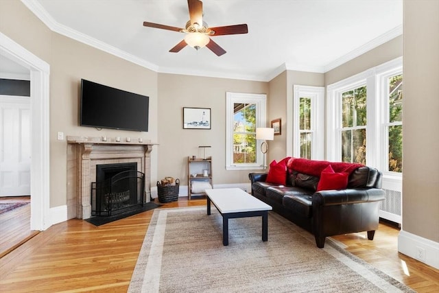 living room featuring a healthy amount of sunlight, light wood-style floors, a ceiling fan, and a fireplace with flush hearth