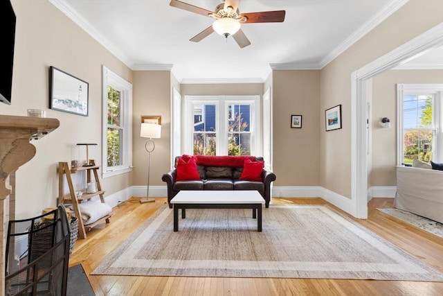 living area with baseboards, plenty of natural light, wood-type flooring, and a ceiling fan
