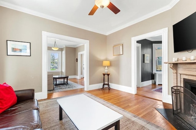 living room featuring baseboards, ornamental molding, a ceiling fan, and hardwood / wood-style floors