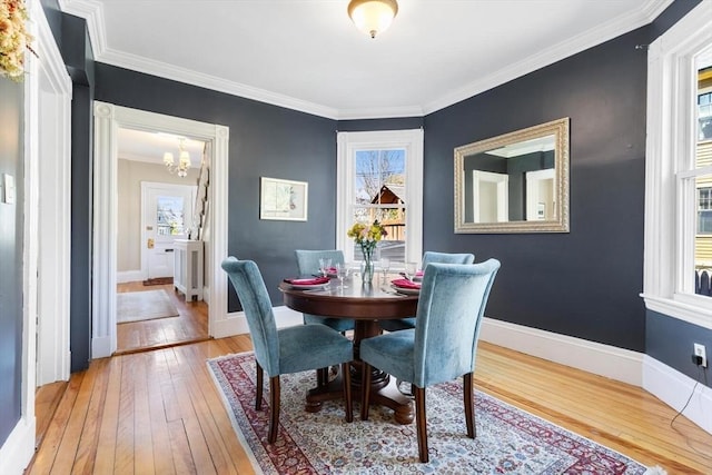 dining area featuring a notable chandelier, plenty of natural light, ornamental molding, and hardwood / wood-style flooring