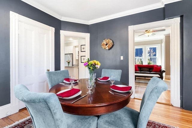 dining space with crown molding, baseboards, ceiling fan, and wood finished floors