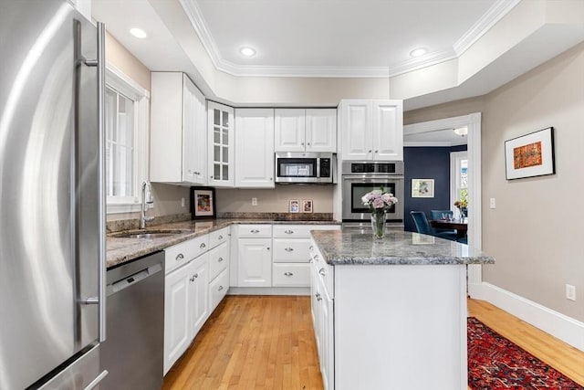 kitchen featuring crown molding, a center island, a sink, light wood finished floors, and stainless steel appliances