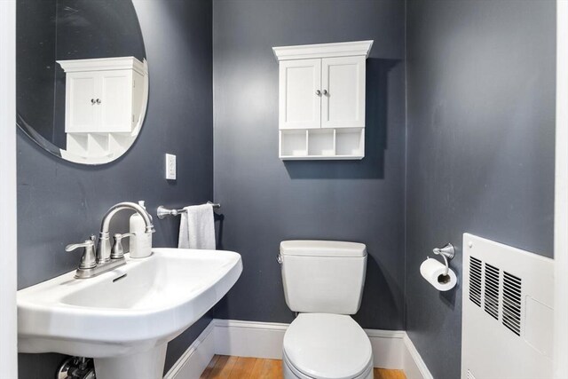 half bath featuring visible vents, wood finished floors, toilet, baseboards, and a sink