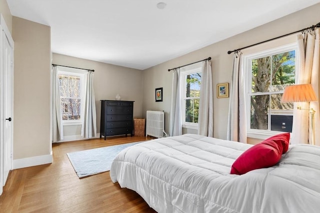 bedroom with radiator, baseboards, and wood finished floors
