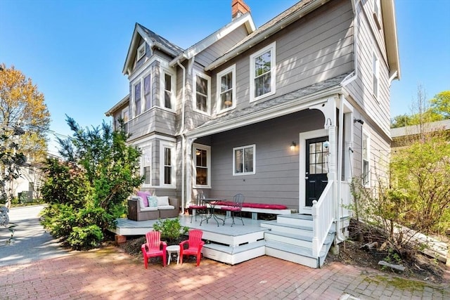 back of house with a chimney, a patio area, and a deck