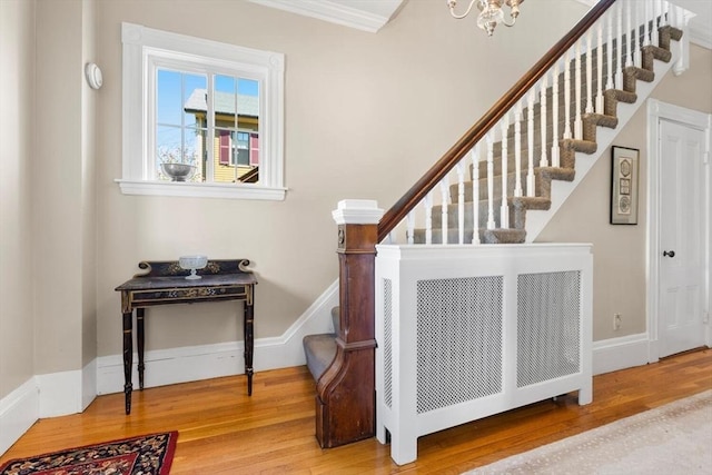 stairway featuring an inviting chandelier, ornamental molding, baseboards, and wood finished floors