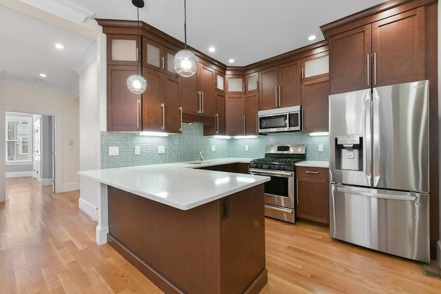 870 E 4th St Unit 1, Boston, MA 02127 - kitchen with stainless steel appliances, ornamental molding, a peninsula, light countertops, and decorative backsplash