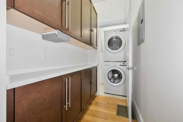 870 E 4th St Unit 1, Boston, MA 02127 - laundry room featuring stacked washing machine and dryer, light wood-style floors, and cabinet space