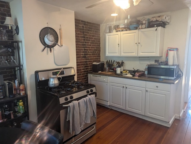 kitchen with ceiling fan, stainless steel appliances, white cabinets, brick wall, and dark hardwood / wood-style floors