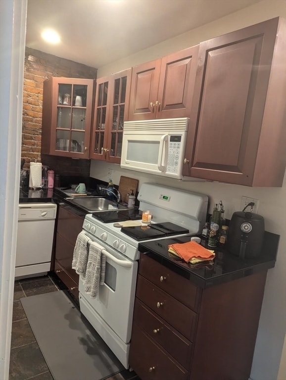 kitchen with white appliances, dark tile patterned flooring, sink, dark brown cabinetry, and vaulted ceiling