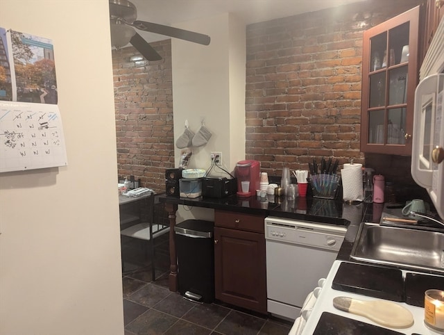 kitchen with dark brown cabinets, ceiling fan, dishwasher, sink, and brick wall