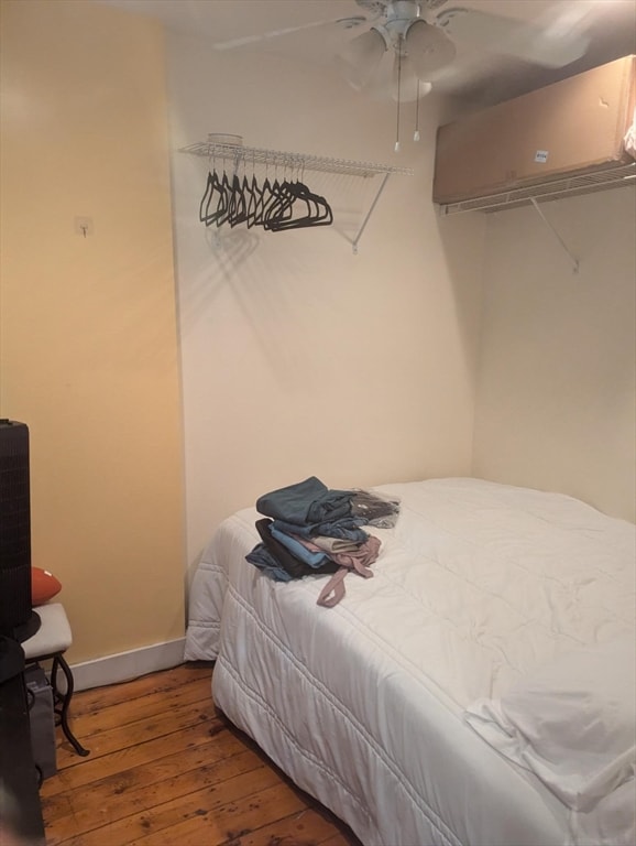 bedroom featuring a wall unit AC, hardwood / wood-style floors, and ceiling fan