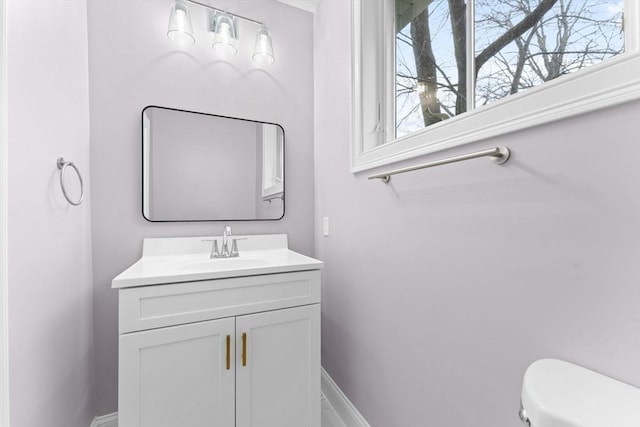 bathroom with baseboards, toilet, and vanity