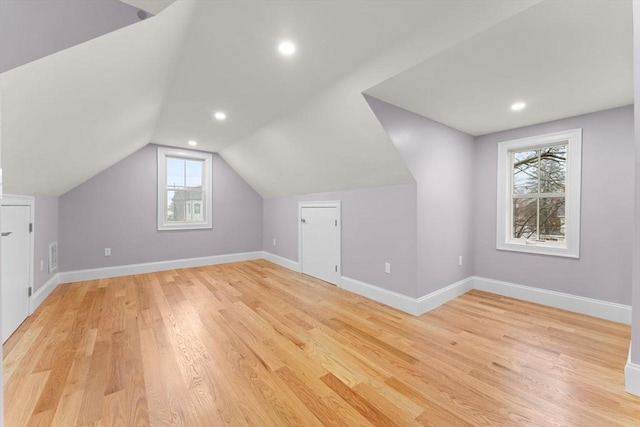 bonus room with plenty of natural light, light wood finished floors, and lofted ceiling
