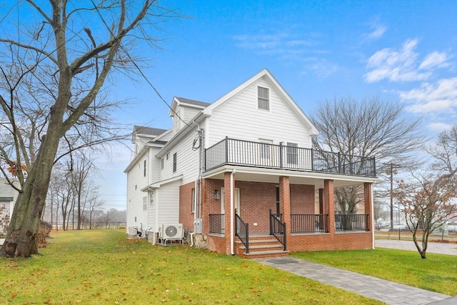 view of front facade with covered porch, a front yard, brick siding, and a balcony