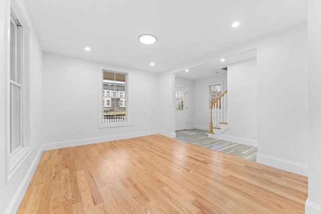 spare room with recessed lighting, baseboards, wood finished floors, and stairway