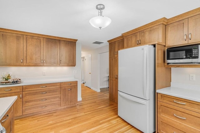4 Fairway Rd, Acton, MA 01720 - kitchen featuring freestanding refrigerator, stainless steel microwave, light wood-style flooring, and brown cabinetry