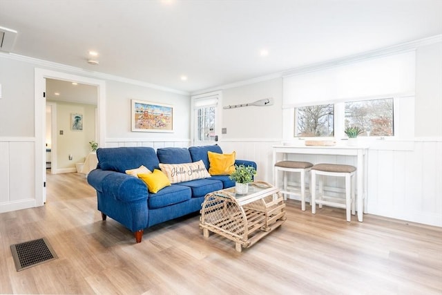 living room featuring crown molding and light hardwood / wood-style flooring