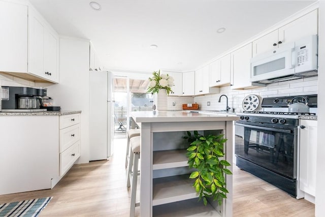 kitchen with white cabinetry, white appliances, a kitchen bar, and decorative backsplash