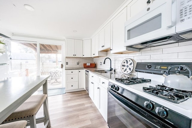 kitchen with sink, range with gas cooktop, white cabinetry, dishwasher, and backsplash