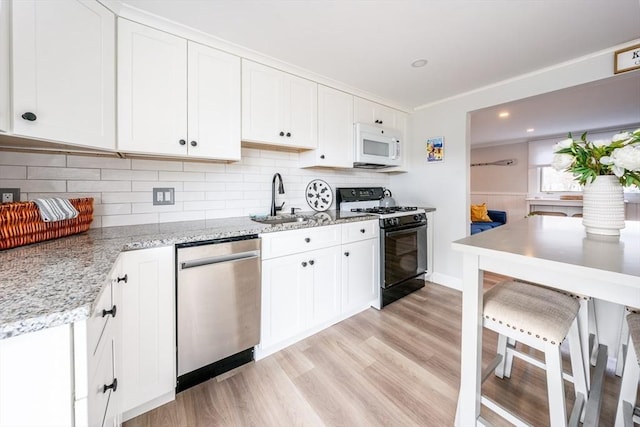 kitchen with sink, stainless steel dishwasher, range with gas stovetop, and white cabinets